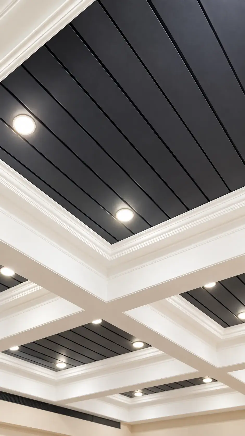 White coffered ceiling with crown mouldings framing charcoal slatted panels and recessed downlights
