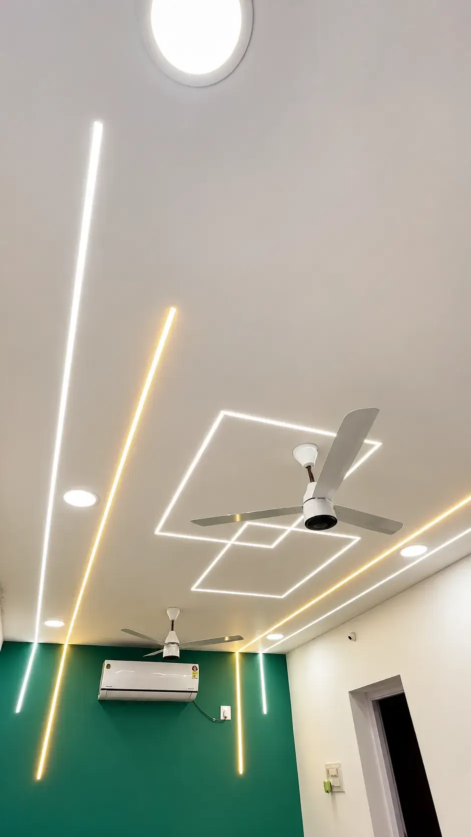 Warm and cool LED light lines running across a white ceiling and down an emerald green feature wall