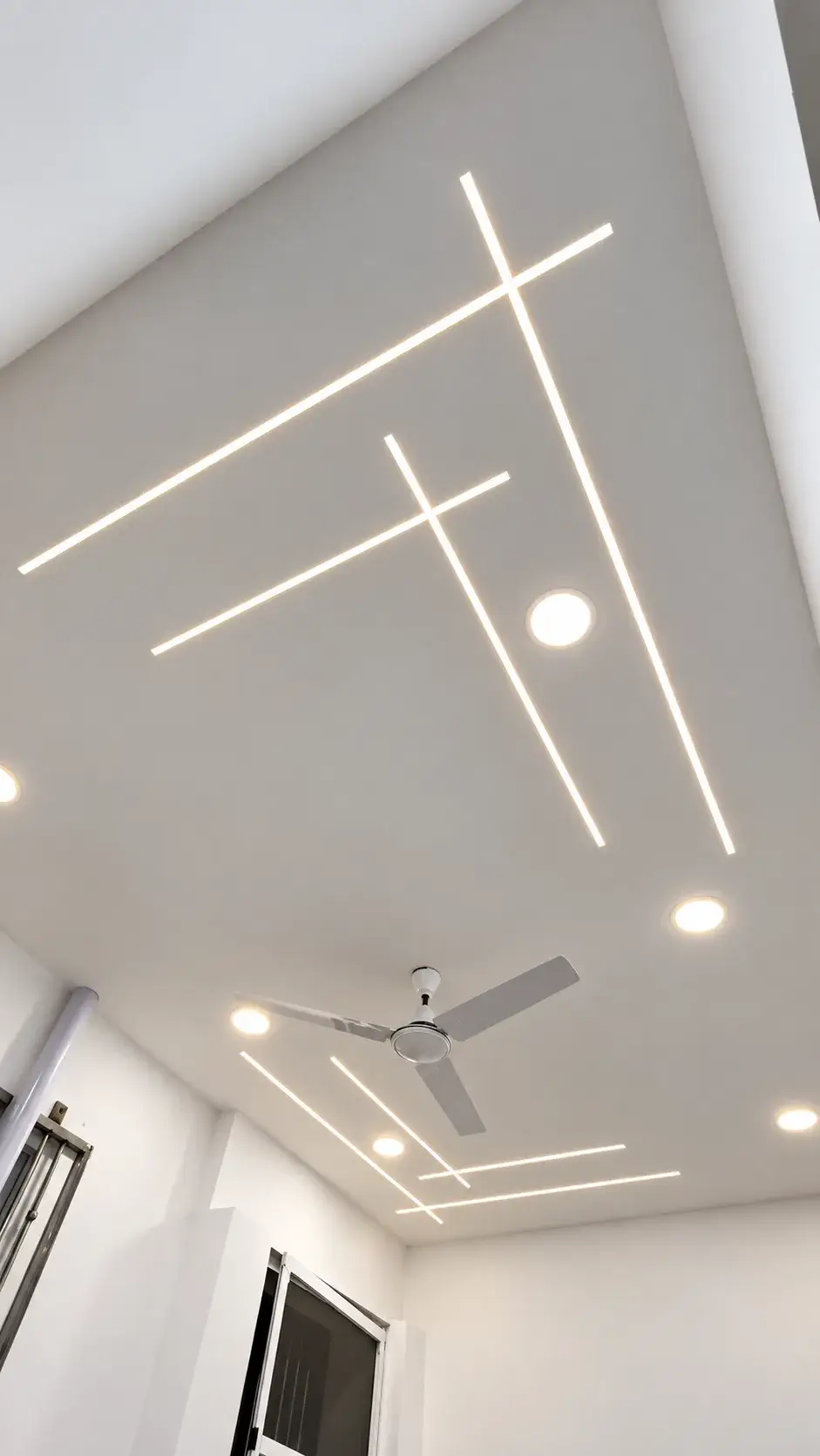 Seamless white gypsum false ceiling with crossing recessed LED profile lights and round downlights